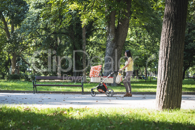 Mother walking in the park with baby buggy