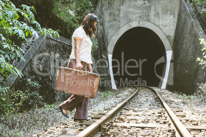 Woman walk on railroad with a suitcase in hands