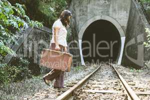 Woman walk on railroad with a suitcase in hands