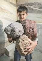Strong child holds heavy stones