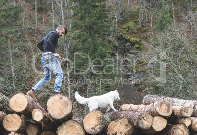 Young man and dog on logs in the forest