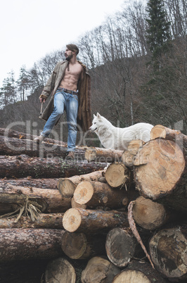 Young man and dog on logs in the forest