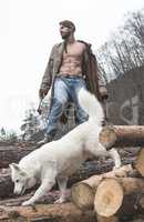 Young man and dog on logs in the forest