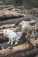 Young man and dog on logs in the forest