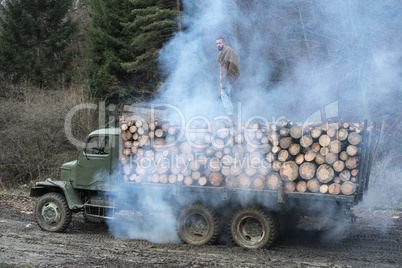 Young man on vintage truck with logs