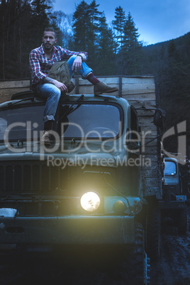 Young man on vintage truck with logs