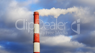 Pipe industrial chimney with smoke against the sky and clouds