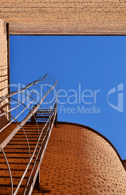 Industrial ladder, blue sky and brick walls of the building