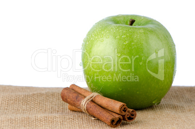 Ripe green apple with cinnamon sticks