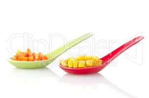 Canned corn and carrot slices on ceramic spoons