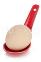 Brown egg in a red ceramic spoon