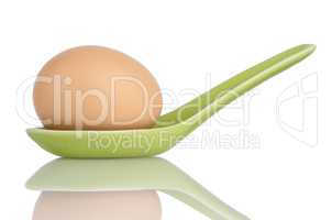 Brown egg in a green ceramic spoon