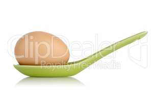 Brown egg in a green ceramic spoon