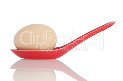 Brown egg in a red ceramic spoon