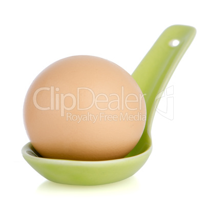 Brown egg in a green ceramic spoon