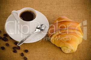 Cup of black coffee and croissant