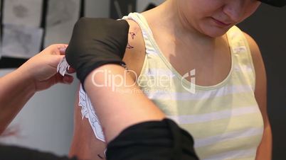 Tattoo artist applying image of a tattoo on a client's arm