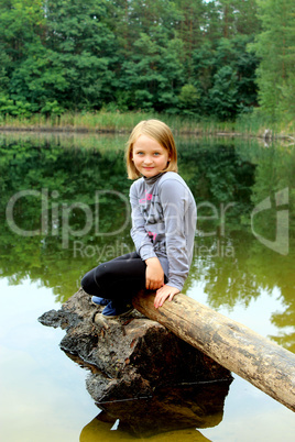 beautiful girl sits on the log by the river