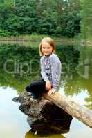 beautiful girl sits on the log by the river