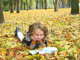 girl reads a book in the autumn park
