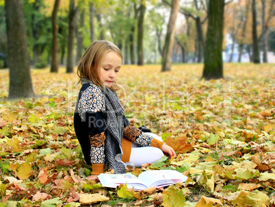 young girl reads a book in the autumn park