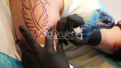 Tattoo artist tracing the image of a feather