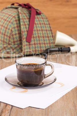 Coffee cup, paper sheets and detective hat