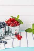 Red currants and blueberries in small metal buckets