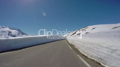 Driving a Car on a Mountain road in Norway with high snow wall