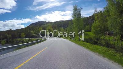Driving a Car on a Mountain road in Norway with high snow wall
