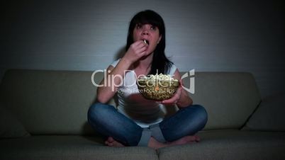 Woman watching movie on couch while eating popcornWoman watching movie on couch while eating popcorn