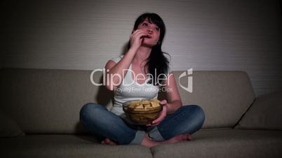 Woman watching movie on couch while eating popcornWoman watching movie on couch while eating popcorn