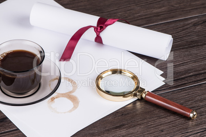 Coffee cup, paper sheets and detective magnifying glass