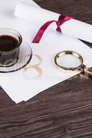 Coffee cup, paper sheets and detective magnifying glass