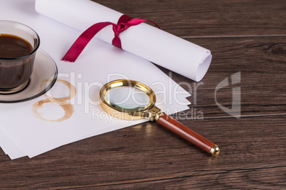 Coffee cup, paper sheets and detective magnifying glass