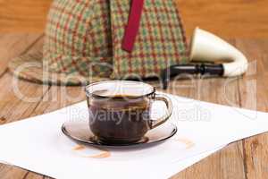 Coffee cup, paper sheets and detective hat