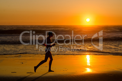 Woman jogger running on sunset beach