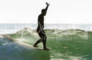 Long boarder surfing the waves at sunset