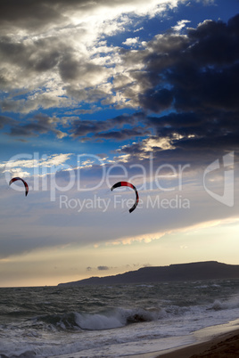 Two silhouette of power kites at sunset sky