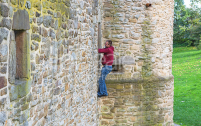 Mann klettert eine Burgmauer hinauf.