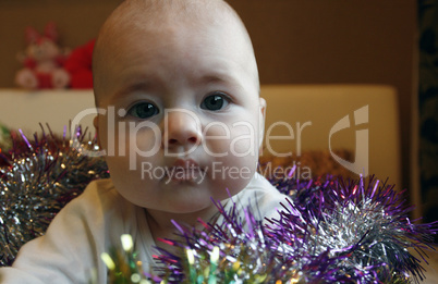 very little cute girl lying in bed with a Christmas garland