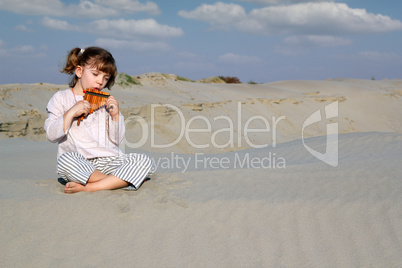 little girl play panpipe in desert