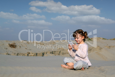 little girl play with tablet pc in desert