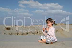 little girl play with tablet pc in desert
