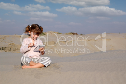 happy little girl play with tablet pc in desert