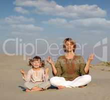 mother and daughter meditating in desert