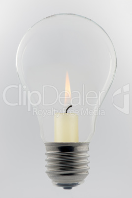 Conceptual glass light bulb with burning candle.