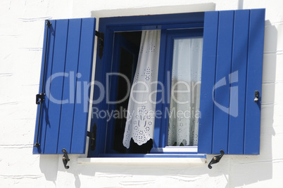 Traditional window with blue shutters in Greece
