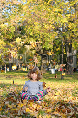 happy little girl fun with autumn leaves