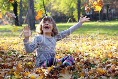 little girl play with autumn leaves